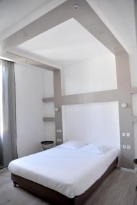 a bedroom with a white bed and white walls at Grand Hôtel in Sainte-Foy-la-Grande