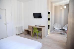 a bedroom with a desk and a tv on a wall at Grand Hôtel in Sainte-Foy-la-Grande