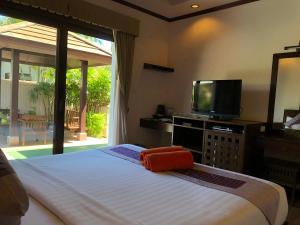 a bedroom with a large bed and a television at Kanok Buri Resort in Lipa Noi