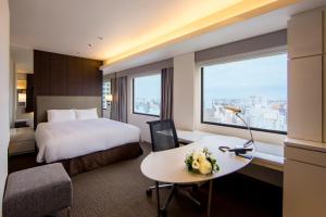 川崎市にある川崎日航ホテルのベッド、デスク、窓が備わるホテルルームです。
