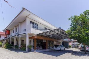un bâtiment blanc avec une voiture garée devant dans l'établissement RedDoorz near Sam Ratulangi Airport Manado, à Manado