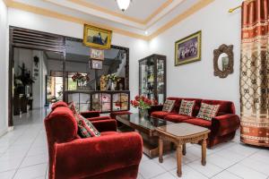 un salon avec des chaises rouges et une table dans l'établissement RedDoorz near Sam Ratulangi Airport Manado, à Manado