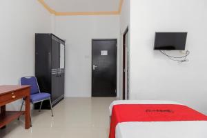 une chambre avec un lit, un bureau et une télévision dans l'établissement RedDoorz near Sam Ratulangi Airport Manado, à Manado 18 autres photos