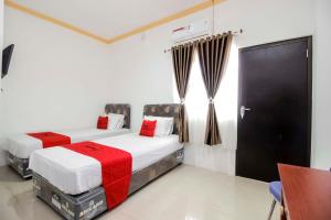 - 2 lits dans une chambre d'hôtel aux accents rouges dans l'établissement RedDoorz near Sam Ratulangi Airport Manado, à Manado