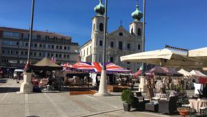 einen Markt mit Tischen und Sonnenschirmen vor einem Gebäude in der Unterkunft Victory in Gorizia