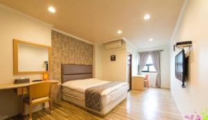 a hotel room with a bed and a desk and a desk at Yilan Jimmy Villa in Yilan City