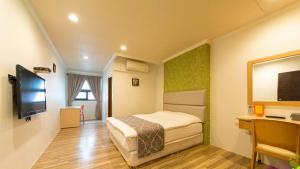 Yilan Jimmy Villa في مدينة ييلان: غرفه فندقيه سرير وتلفزيون