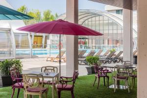 un patio con tavoli, sedie e ombrellone viola di Madrid Airport Suites, Affiliated by Meliá a Madrid