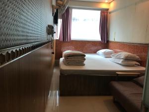 Habitación pequeña con 2 camas y ventana en New Garden Hostel, en Hong Kong