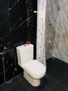 a white toilet in a bathroom with a black wall at Seagull's Nest in Tangalle