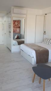 トレモリノスにあるEstudiosol40の白いベッドルーム(ベッド2台、テーブル付)