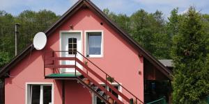 a red house with a white window and stairs at Podkroví - ubytování Brdy in Bohutín