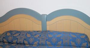 a bed with a blue comforter against a wall at Residence Porto Mannu in Palau