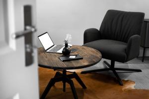 a wooden table with a laptop and a chair at Logierhaus M in Esens