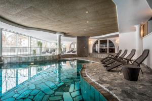 basen z krzesłami w budynku w obiekcie Kristallhotel Corona-Krone w mieście San Vigilio di Marebbe