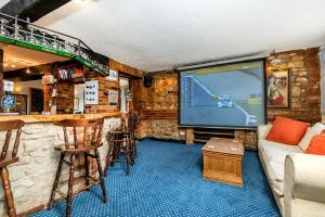 a living room with a bar and a large screen television at The Inn With The Well in Marlborough