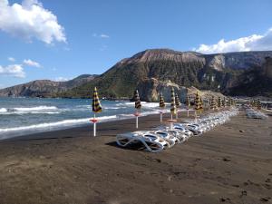 una fila di ombrelloni e sedie sulla spiaggia di Case Vacanze Levante a Vulcano