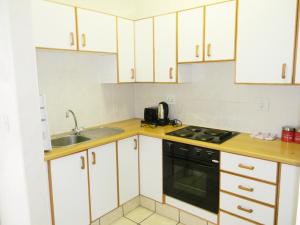 cocina con armarios blancos y fogones negros en Dumela Margate Flat No 14, en Margate