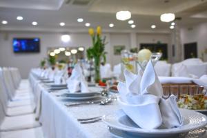 einen langen Tisch mit weißen Tellern und Servietten darauf in der Unterkunft Hotel Słowik in Poniatowa
