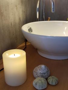 Una vela y dos piedras en un baño con lavabo. en aurora suite, en Nyksund