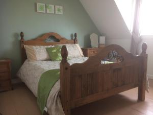 a bedroom with a wooden bed with a wooden headboard at Seascape Cottage in Knock