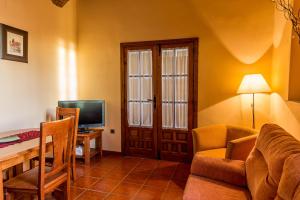 a living room with a couch and a desk with a television at Casa Rural Caseta de los Camineros in Garrovillas