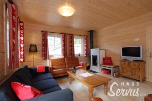 a living room with a couch and a tv at Haus Servus in Klösterle am Arlberg