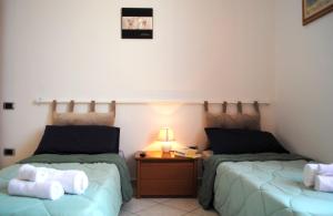 Habitación con 2 camas y mesa con lámpara. en BNBOOK - BORROMEO 1, en Rho