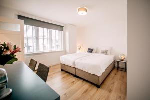 een witte slaapkamer met een bed en een tafel bij Zylt Zandvoort in Zandvoort