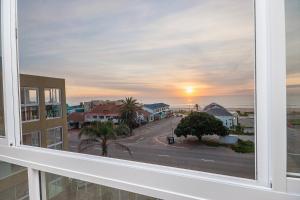 a view from a window of a street with a sunset at Main Beach Penthouse in Jeffreys Bay