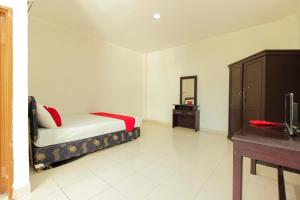 a bedroom with a bed and a dresser and a mirror at RedDoorz @ Malalayang Manado in Manado