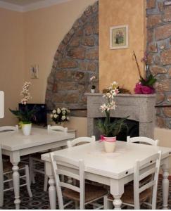 a restaurant with white tables and chairs and a fireplace at Guest House Le Gemelle in Luras