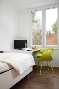 a bedroom with a bed and a desk and a green chair at Rosa Flesch Hotel und Tagungszentrum in Waldbreitbach