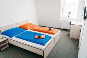 チェスケー・ブジェヨヴィツェにあるHC Hotelのベッドルーム1室(オレンジとブルーのシーツを使用したベッド2台付)