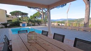 une table et des chaises en bois sur une terrasse avec une piscine dans l'établissement villa claire de lune la Nartelle, à Sainte-Maxime