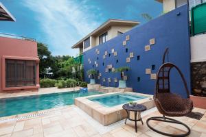 a swimming pool with a chair and a blue wall at StayVista's Villa 39 - A stylish villa with an outdoor pool in Lonavala