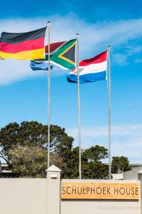 twee vlaggen vliegen voor een gebouw bij Schulphoek Seafront House in Hermanus