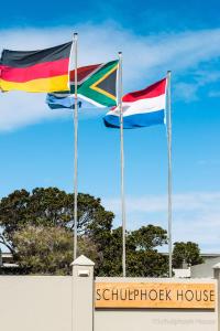 two flags are flying in front of a building at Schulphoek Seafront House in Hermanus