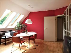 uma sala de jantar com paredes vermelhas e uma mesa e cadeiras em Ferienwohnung Ringbergblick em Suhl