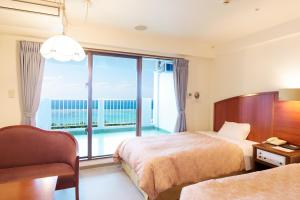 a hotel room with two beds and a large window at Kanehide Onna Marine View Palace in Onna