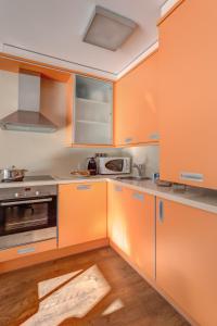 a kitchen with orange cabinets and a microwave at Pierre & Vacances Andorra Bordes d’Envalira in Bordes d´Envalira 