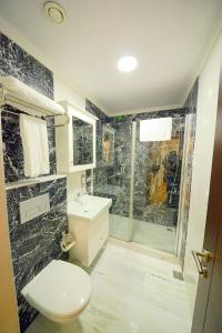 e bagno con servizi igienici, lavandino e doccia. di Sarajevo Suit Hotel a Kocaeli