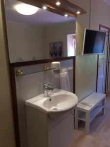 a bathroom with a sink and a mirror and a tv at Hotell Paradis in Eksjö