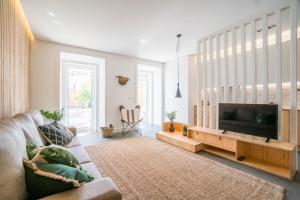 uma sala de estar com um sofá e uma televisão de ecrã plano em Wood Wall & Garden Apartment em Lisboa