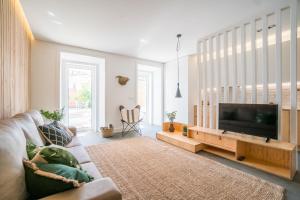 sala de estar con sofá y TV de pantalla plana en Wood Wall & Garden Apartment, en Lisboa