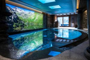- une grande piscine dans une maison avec une grande télévision dans l'établissement La Bouitte - Hôtel Relais & Châteaux, à Saint-Martin-de-Belleville