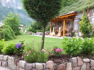 un jardin avec des fleurs et un mur en pierre dans l'établissement Appartamenti Donini Alfredo, à Molveno