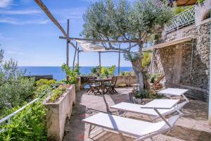 een patio met tafels en stoelen en de oceaan bij Star Fish House in Amalfi