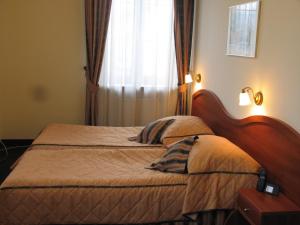 a bedroom with a bed with a wooden headboard and a window at Hotel Saol in Krynica Zdrój