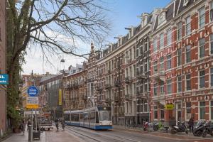 a bus driving down a city street with buildings at Marnix360apartments Design in Amsterdam